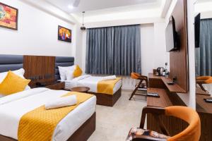 a hotel room with two beds and a desk at Hotel Palash in Greater Noida