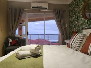 a bedroom with a bed with a view of the ocean at Lamer Holiday Apartment 66 in Kingsburgh