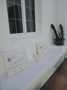 due cuscini seduti su una mensola bianca con due finestre di Casa Strelitzia a Nazaret