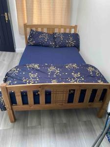 ノースウッドにあるGreat Place in Northwoodの青い掛け布団が備わるドミトリールームの木製ベッド1台分です。