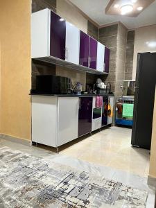 kuchnia z białymi szafkami i fioletowymi urządzeniami w obiekcie Sasha House w Kairze