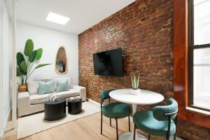 uma sala de estar com uma parede de tijolos e uma mesa e cadeiras em 153-5A Charming 2BR LES W D em Nova York