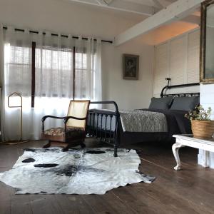 1 dormitorio con 1 cama, 1 silla y 1 alfombra en Urban Plett, en Plettenberg Bay