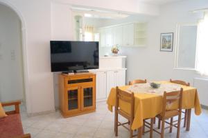 a living room with a television and a table with chairs at Maria & Kyros House in Parga