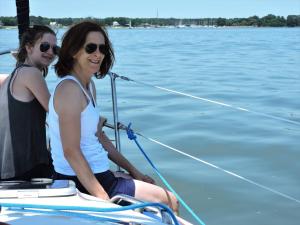 dos mujeres sentadas en un barco en el agua en Williamsburg Charter Sails / Let's Go Sail, 