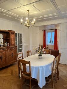 une salle à manger avec une table et un vase de fleurs. dans l'établissement Villa 18.78, 10 min de la Suisse, à Damprichard