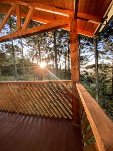 a wooden deck with the sun shining through the trees at Casa de Campo Santa Paulina in Urupema