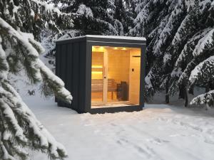 a black cabin in the snow in a snowy forest at Pillow House Montibus in Pribylina