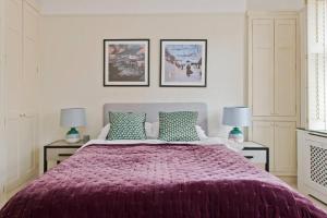 um quarto com uma cama grande e um cobertor roxo em Stylish London Getaway in the Heart of the City em Londres