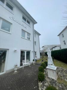 a white building with a statue in front of it at Apartmenthaus Sonnenblick in Binz