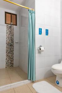 a bathroom with a shower curtain and a toilet at Hotel Pelican Bay in Puerto Ayora