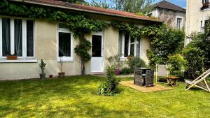 uma casa com um relvado com um grelhador no quintal em L Annexe - Parenthèse Champêtre PARIS DISNEYLAND em Gagny