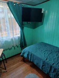 um quarto com uma cama e uma televisão de ecrã plano em Habitación cómoda por día em Valdivia