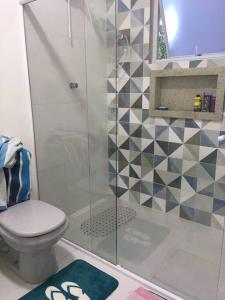 a bathroom with a shower with a toilet and a rug at Casa de Praia in Cananéia