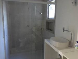 a bathroom with a shower with a sink and a toilet at Casa de Praia in Cananéia