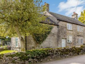 an old stone house with a tree in front of it at 3 Bed in Wetton 79554 in Wetton