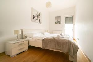 a white bedroom with a bed and a night stand at Trendy apartment 5 min to city centre!` in Zagreb