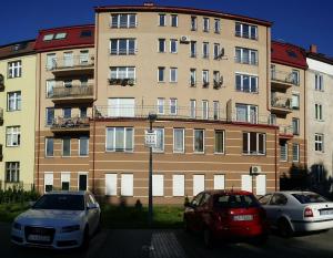 two cars parked in front of a large building at Apartament Słupsk in Słupsk