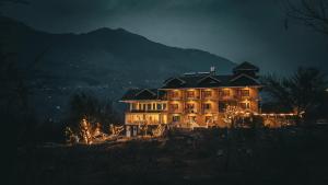 a large house is lit up at night at Aroha Residency- A Countryside Resort in Manāli