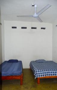 two beds in a room with a ceiling fan at Hostal Madrid in Tapachula