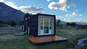 a tiny house sitting on top of a field at La Carmela Container house's in Esquel