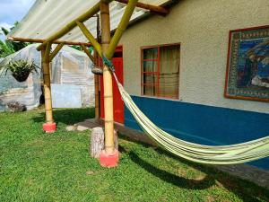 a hammock in the grass in front of a house at Alojamiento Rural Finca El Rubi- Eje cafetero in Quimbaya