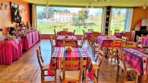 a dining room with tables and chairs and a large window at Hotel Pumakala in Puno