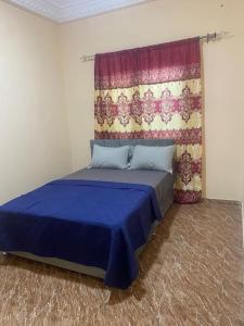 una camera con letto blu con tenda di Izzy Guest House a Brikama