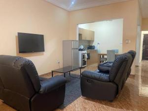 - un salon avec deux chaises et une télévision dans l'établissement Izzy Guest House, à Brikama