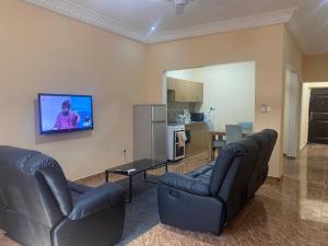 a living room with two couches and a tv on the wall at Izzy Guest House in Brikama