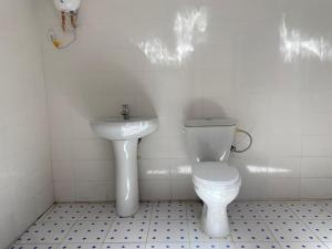 La salle de bains blanche est pourvue de toilettes et d'un lavabo. dans l'établissement Izzy Guest House, à Brikama
