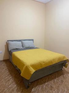 a bedroom with a bed with a yellow blanket on it at Izzy Guest House in Brikama