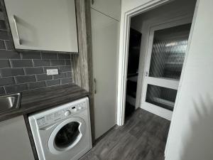 Waschmaschine und Trockner in einem kleinen Zimmer mit Tür in der Unterkunft Noormak nights in Birmingham