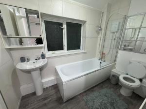 a bathroom with a sink and a tub and a toilet at Noormak nights in Birmingham