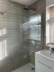 a bathroom with a glass shower and a sink at Bright and sunny village home in Ipplepen