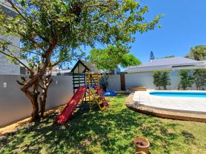 a backyard with a tree and a swing at Casa em Atlântida com Piscina in Xangri-lá