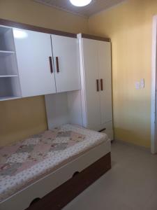 Schlafzimmer mit einem Bett und weißen Schränken in der Unterkunft Casa em Atlântida com Piscina in Xangri-lá + 50 Fotos