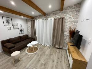 a living room with a couch and a brick wall at Maison plain pied au calme in Cuges-les-Pins