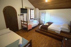 a bedroom with two beds and a tv in it at Pousada Sobradinho in Tiradentes