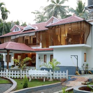 a house with a white fence in front of it at Thekkumbath Sea Breeze Pool villa in Kannur