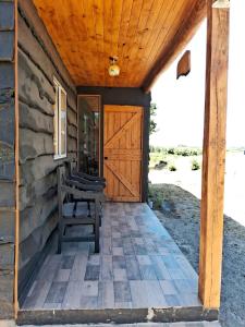 a wooden door to a cabin with a bench on a porch at Cabañas Vista Horizonte in El Durazno