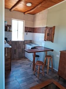 a kitchen with a table and two stools at Cabañas Vista Horizonte in El Durazno