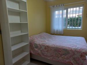 a bedroom with a bed and shelves and a window at Casa em Atlântida com Piscina in Xangri-lá