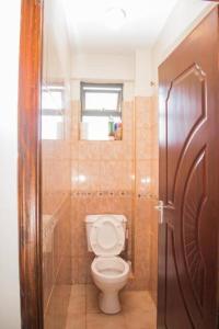 a bathroom with a toilet and a window at Gem in Busia +11 photos
