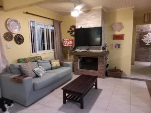 ein Wohnzimmer mit Couch und Flachbildfernseher in der Unterkunft Casa em Atlântida com Piscina in Xangri-lá