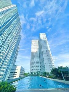 two tall buildings and a swimming pool between two buildings at The Grass Residences in Manila