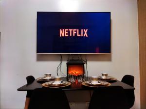 a television on a wall above a table with plates and glasses at The Grass Residences in Manila