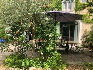 a patio with a table and chairs and an umbrella at 140 du Ventoux in Saint-Saturnin-lès-Avignon
