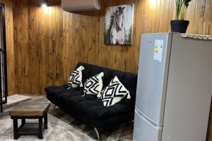 a living room with a black couch and a refrigerator at Domo en el rincón del paraíso in Ranco