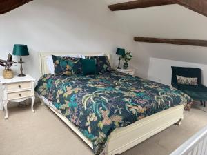 a bedroom with a bed with a flowered comforter at Tregwylan in Nefyn